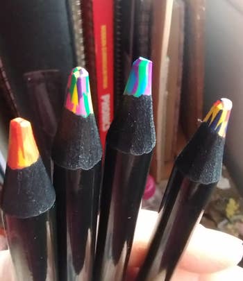 A person holding a set of colored pencils with multicolored tips