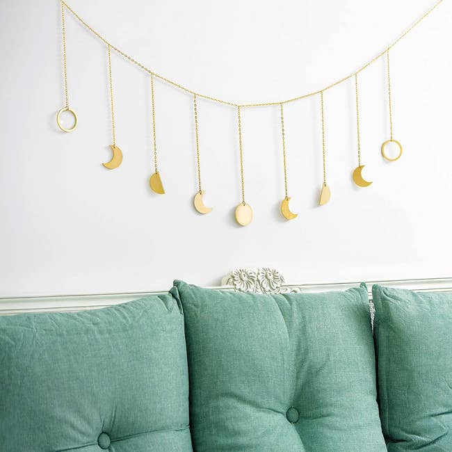 gold-tone dangling moon garland above couch with light blue cushions