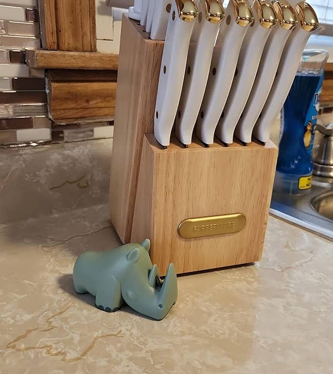 Reviewer's kitchen counter with a wooden knife block and knives, next to a green rhino-shaped knife sharpener