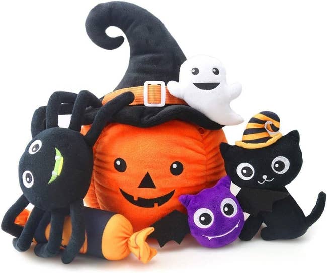 the six stuffed toys including a pumpkin, a bat, a black cat, a spider, a ghost, and a piece of candy