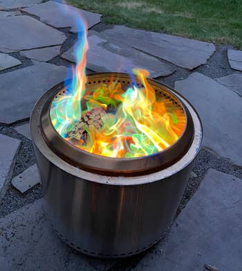 A small outdoor fire pit with rainbow flames 