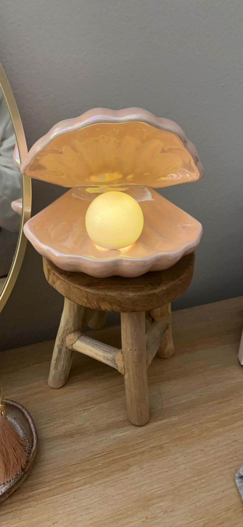Glowing pearl-shaped light inside a clam shell lamp on a wooden stool