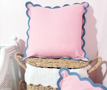 Pink cushion with bluish scalloped trim connected wicker baskets successful a buying display
