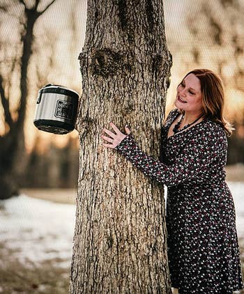 Reviewer gazing happily at their rice cooker while leaning against a tree