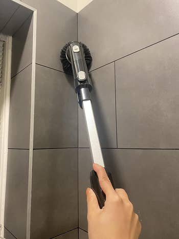 reviewer showing the spin brush cleaning the top of the shower