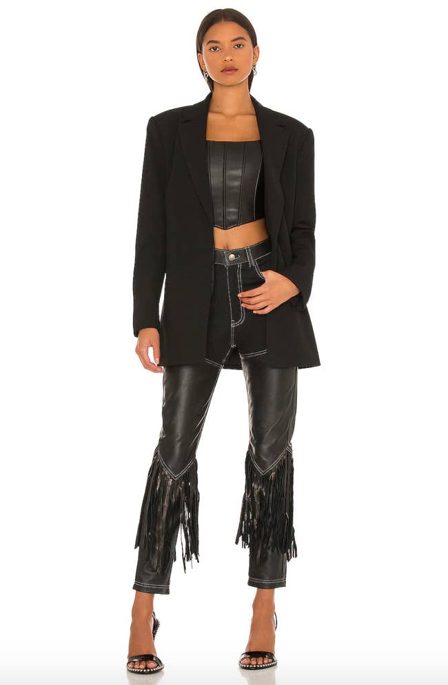 model wearing black leather chaps with fringe and black blazer