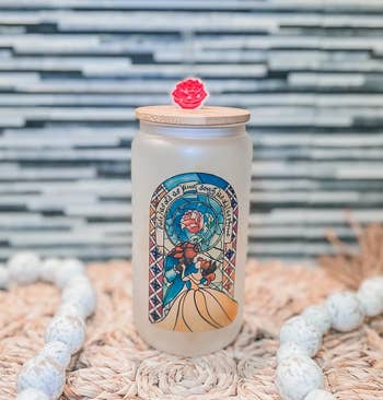 a frosted glass can with a beauty and the beast stain glass design on it