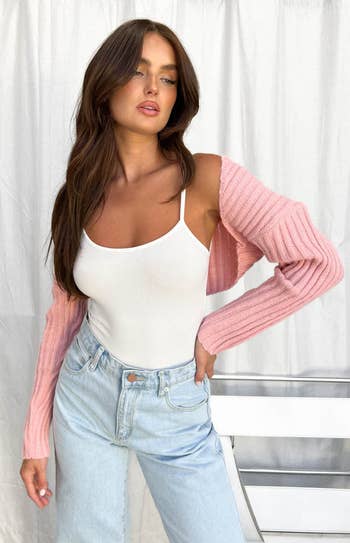 another model wearing the pink bolero with a white tank and blue jeans