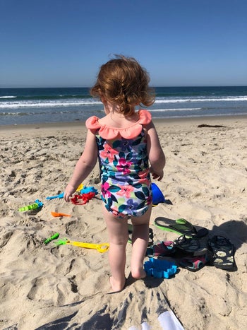reviewer photo of their kid walking towards toys in the sand on a beach