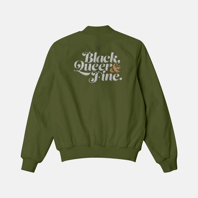 olive green bomber jacket with text black, queer, and fine on back