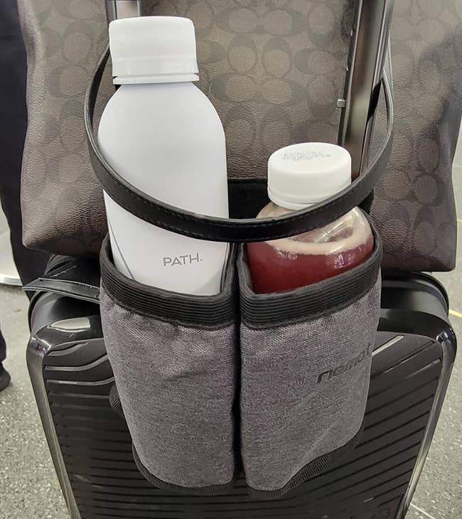 Travel luggage with two water bottles in front pockets, positioned against a suitcase handle. This image is used in a shopping article