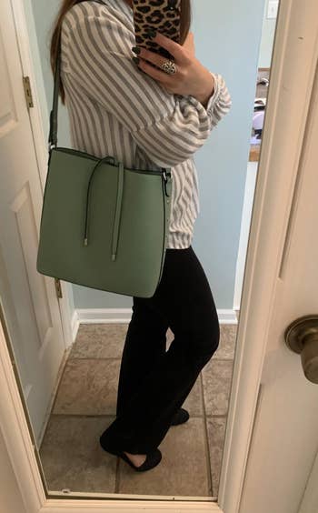 a reviewer wearing the purse in mint green on their shoulder 