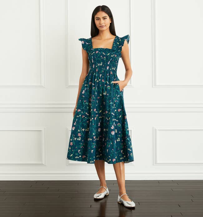 a model in a teal/green mid-length dress with flutter sleeves and a floral print