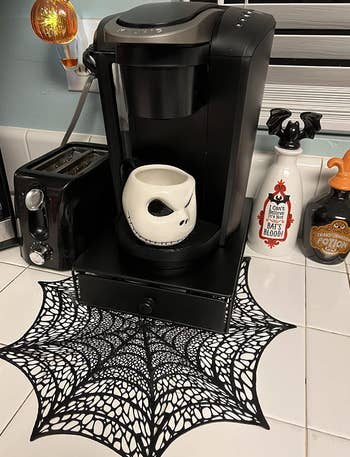reviewer's coffee maker with spider web mat underneath 