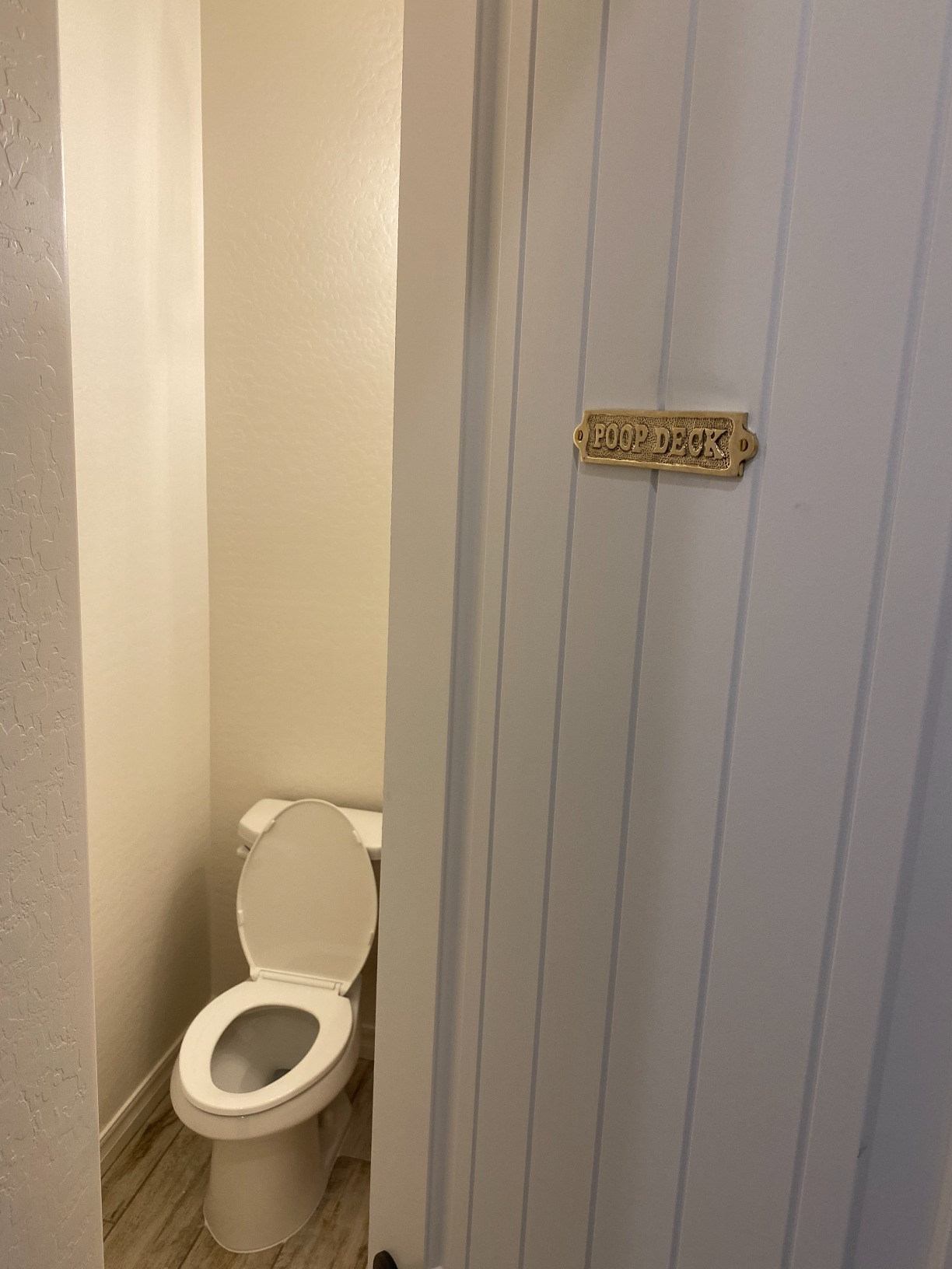 Bathroom doorway  somewhat  ajar with humorous 