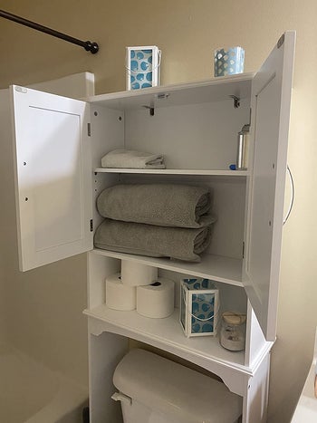 the same reviewer shows the inside on the unit, holding towels and toilet paper
