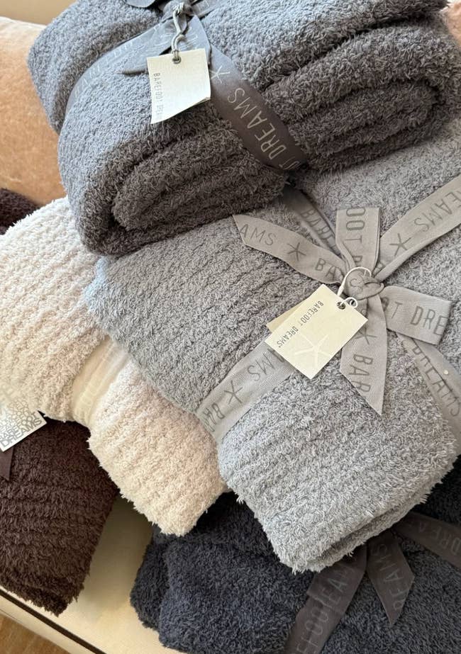 Stack of plush towels tied with branded ribbons, showcasing a assortment  of textures and neutral tones