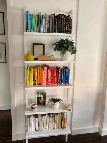 reviewer photo of the white shelves holding colorful books and small decorative items
