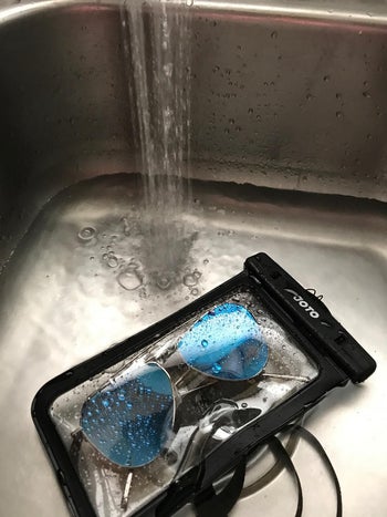Sunglasses inside the case as water from a faucet sprays on it