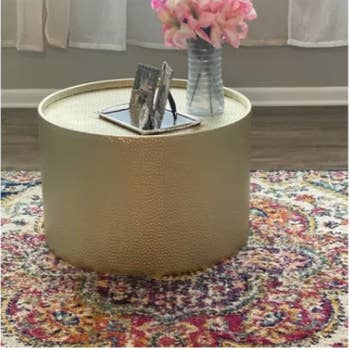 round gold table with flowers and picture frames on it in a reviewer's home