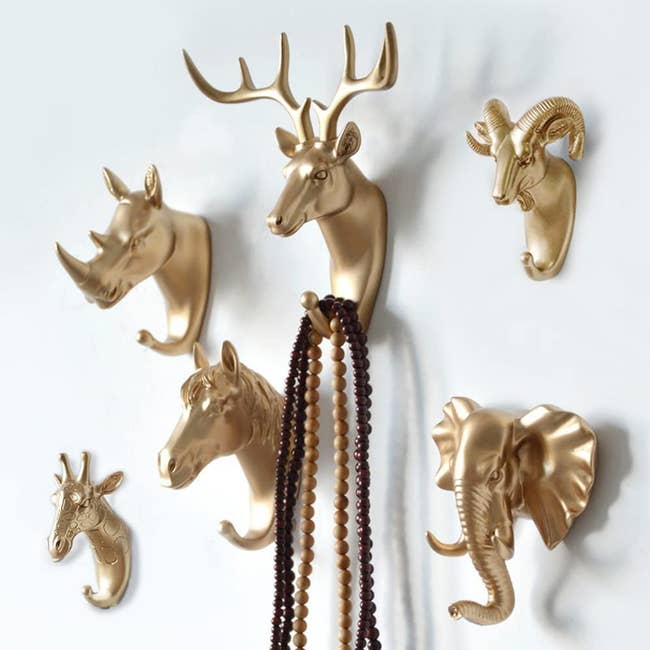 faux gold animal wall hooks shaped like a rhino, deer, ram, horse, elephant, and giraffe