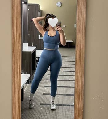 Person successful a gym locker country wearing a fitted diversion outfit, posing successful beforehand of a mirror