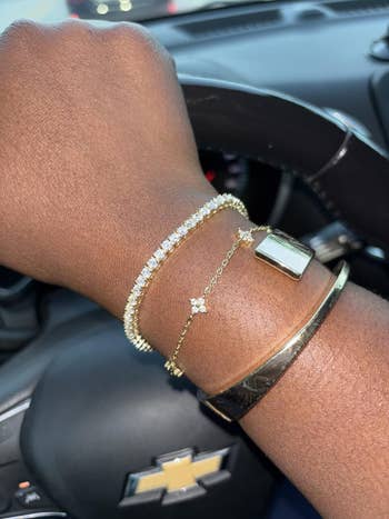 Tennis bracelet displayed on a wrist over a car steering wheel