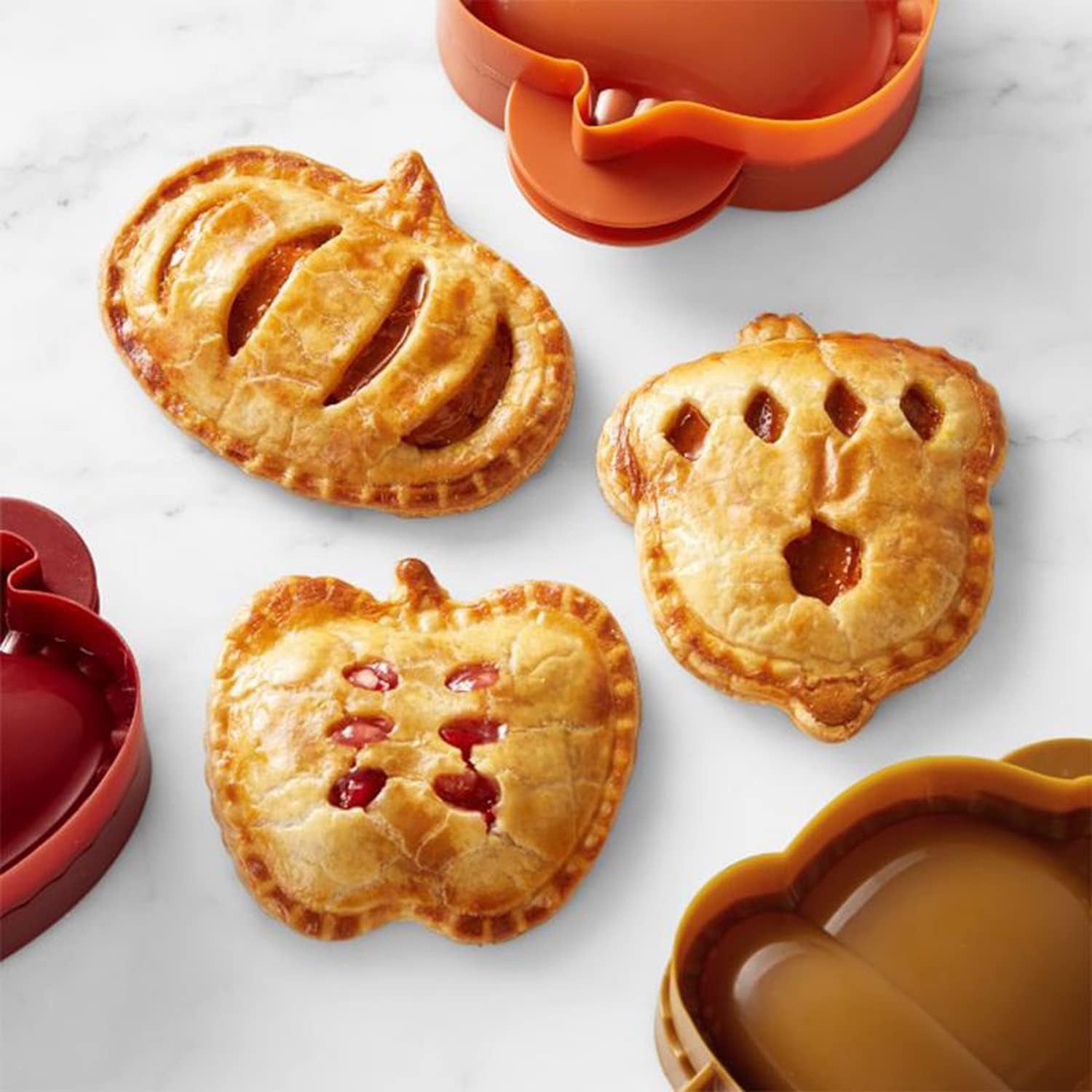 three mini pies shaped like a pumpkin, an acorn, and an apple