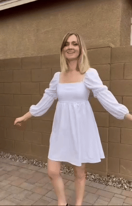 reviewer in a casual white dress with long sleeves and a square neckline