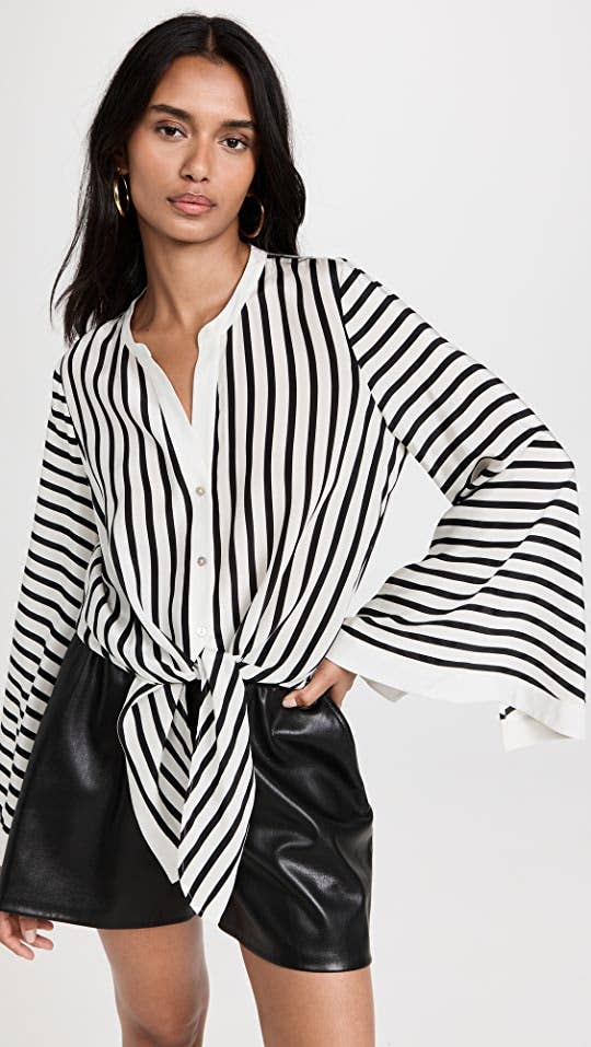 model in black and white collarless button down bell sleeve top with tie at waist