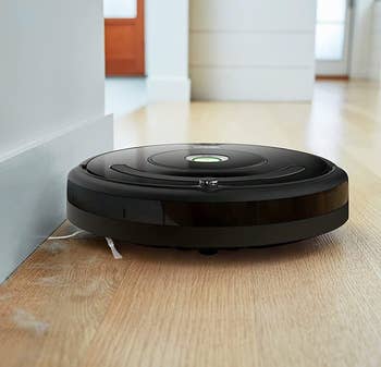 the roomba sweeping up dust bunnies from a wooden floor