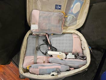 reviewer photo of the pink packing cubes in their luggage