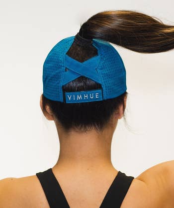 Model showing back of the hat where there's a cross hatch design to support a high ponytail 