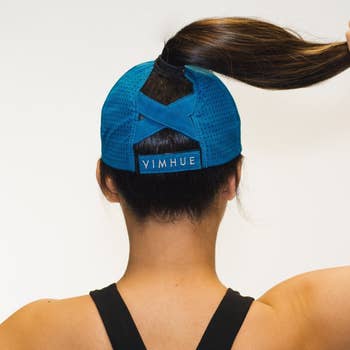 Model showing back of the hat where there's a cross hatch design to support a high ponytail 