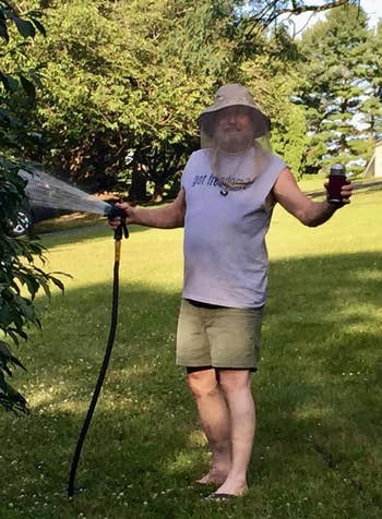 Reviewer is wearing the hat while watering a lawn