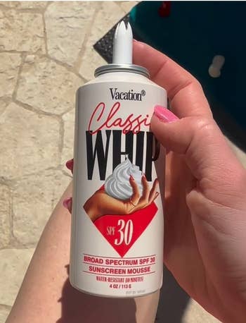 Person holding a can of sunscreen mousse labeled 