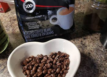 Reviewer photo of a medium roast espresso coffee beans in a cup-shaped bowl beside their packaging