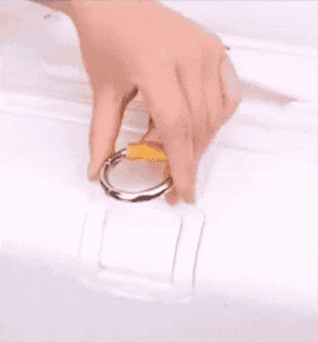 gif showing a model attaching a yellow strap to a white suitcase and hooking a black tote bag to it