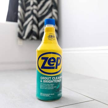 A bottle of Zep Grout Cleaner and Brightener on a floor beside a black and white striped towel