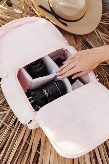 the open pink backpack holding parts of a DSLR camera in its various compartments