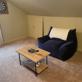 reviewer photo of a navy blue bean bag chair with a coffee table in front of it