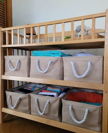 another reviewer's six beige organizers on  the two shelves beneath a baby changing table