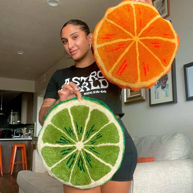 Someone holding up an orange pillow and a lime pillow