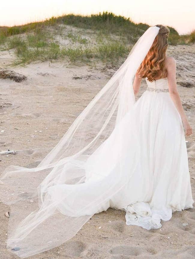 a model wearing the veil while walking on the beach 
