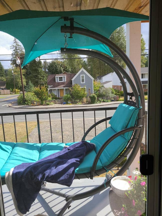 A structure plaything with a canopy, cushions, and a propulsion blanket, overlooking a serene thoroughfare view. Ideal for outdoor relaxation