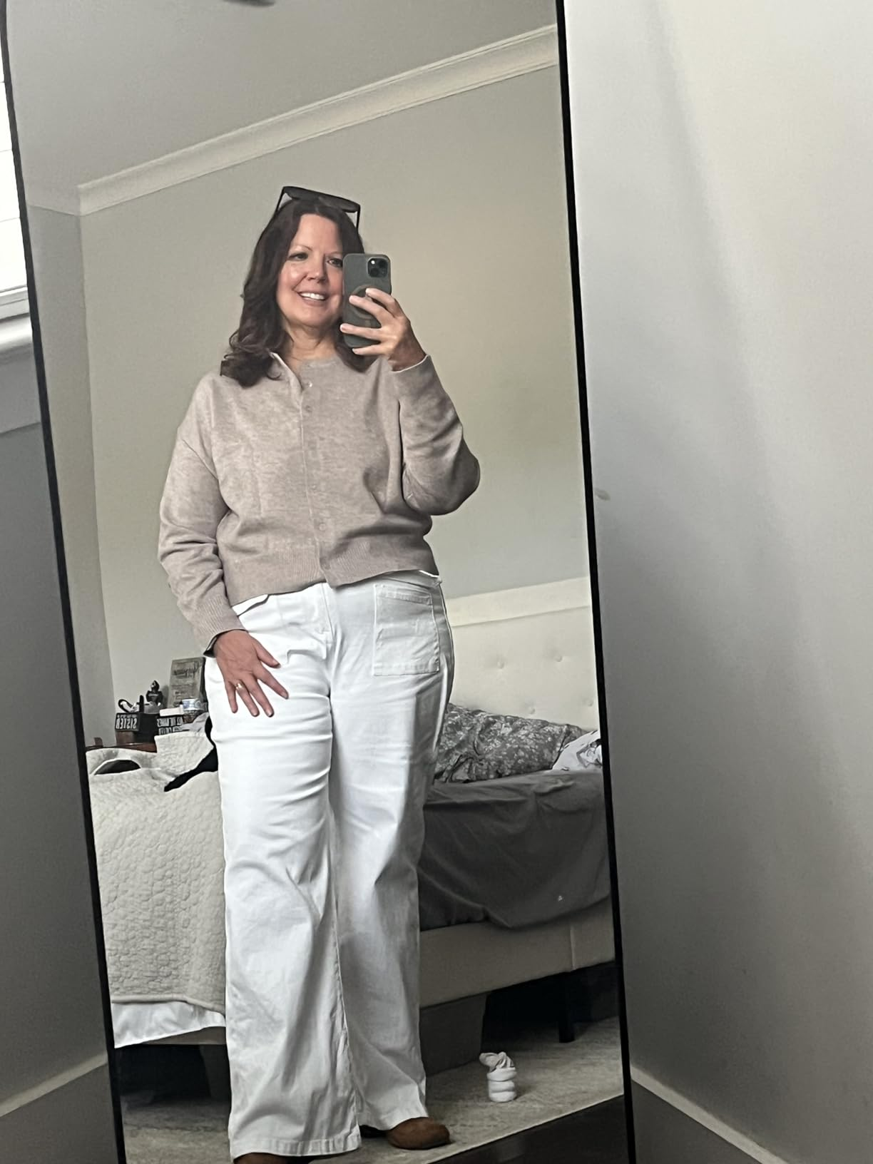 A idiosyncratic   takes a reflector  selfie wearing a casual, cozy outfit with a sweater and wide-leg pants, lasting  successful  a bedroom