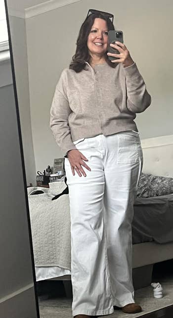 A idiosyncratic takes a reflector selfie wearing a casual, cozy outfit with a sweater and wide-leg pants, lasting successful a bedroom