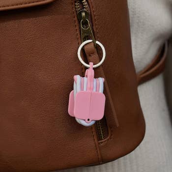 A pink hair tie holder attached to a purse zipper 