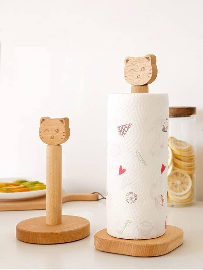 Two wooden paper towel holders with cute cat head designs, one holds a roll