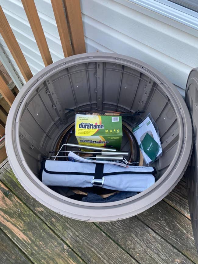 Top-down view of a storage bin containing various items including a duraflame box, book, and clothing, useful for organizing goods